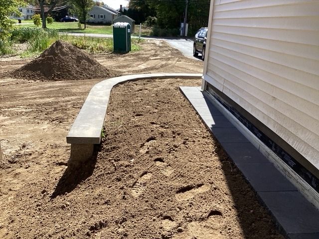 Soil graded around a new house, beside a block wall