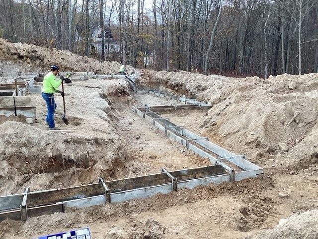 Crew setting footing forms in a trench