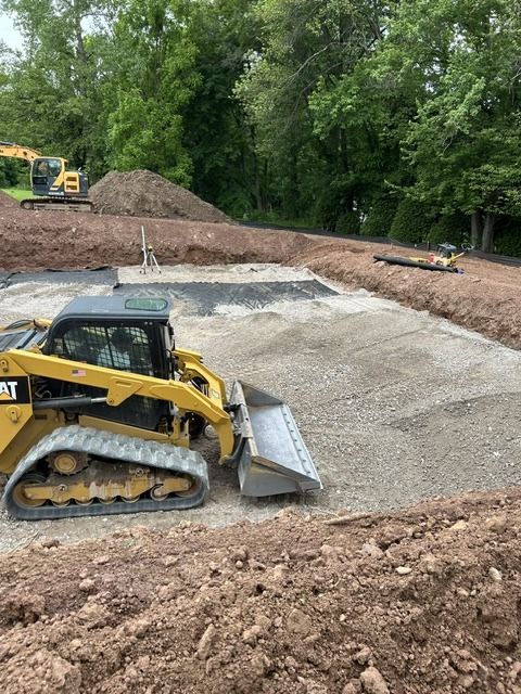 Excavation contractor's skid steer spreading stone in a foundation hole