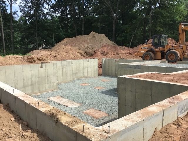 Poured foundation walls with a stone floor base, and a loader behind