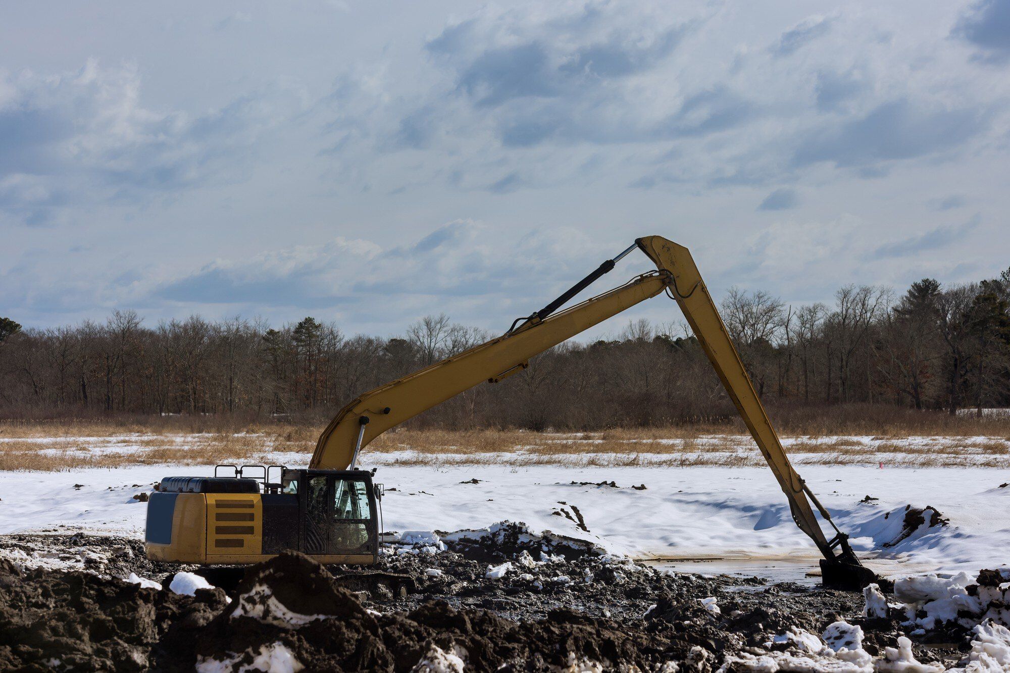 Long-reach excavator working on an open site in winter