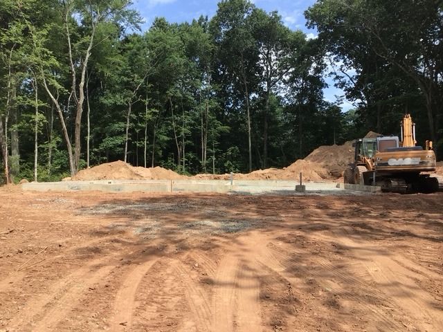 New foundation on a cleared lot, with the excavator beside the spoil piles